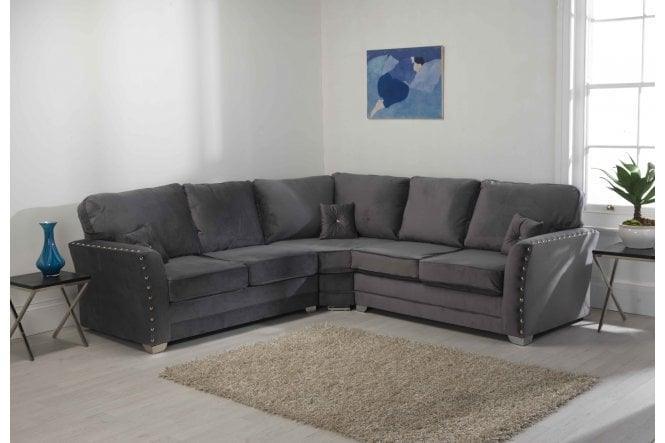 Grey corner sofa with plush cushions in a modern living room, studded detail, two side tables