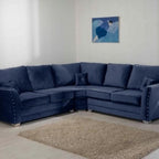 Grey corner sofa with nailhead trim in modern living room, textured rug, wall art