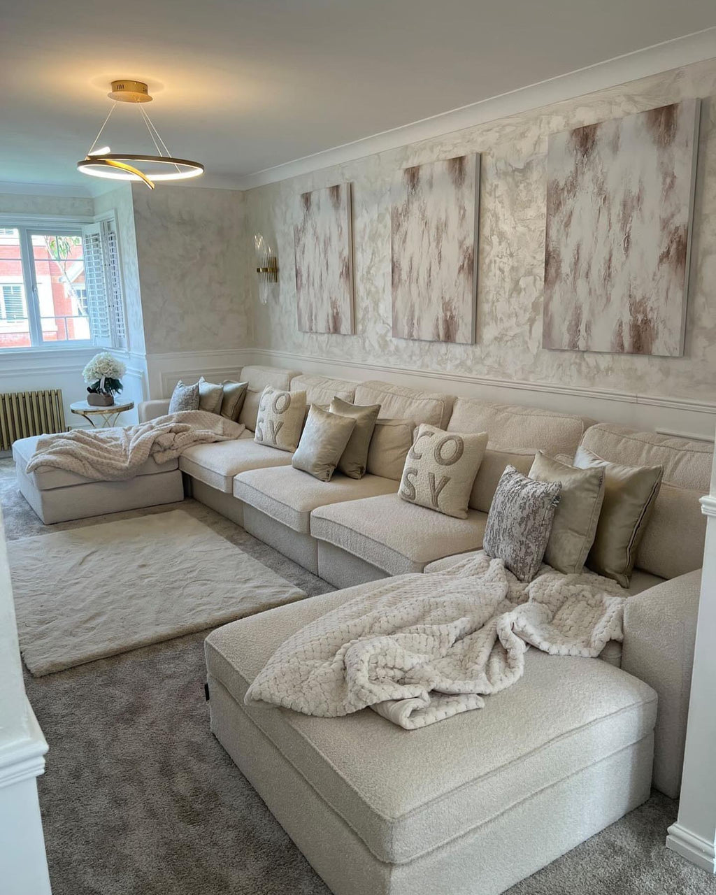 Large cream U-shaped boucle sofa in elegant living room with neutral décor and modern lighting