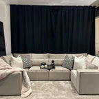 Large cream U-shaped sofa with geometric cushions, throw blanket, and tray in a modern living room.