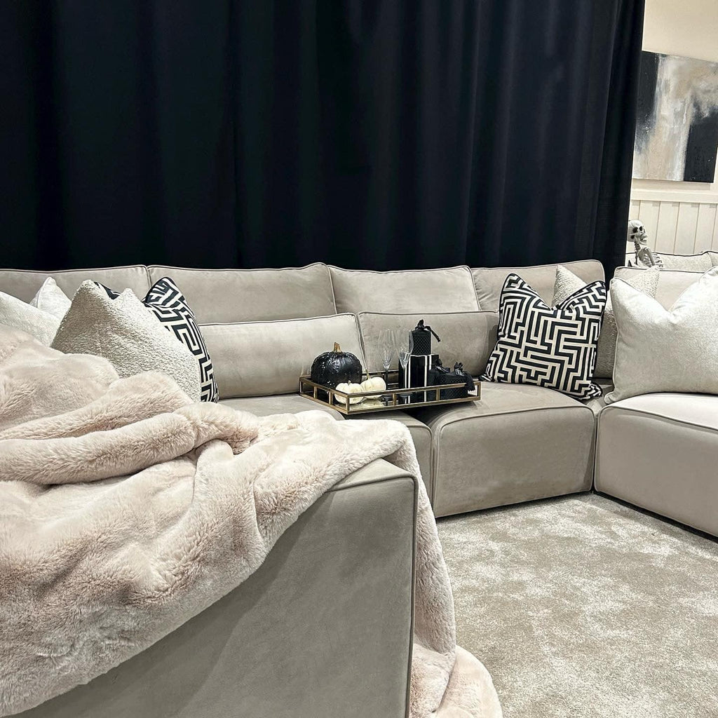 Cream U-shaped sectional sofa with plush throw, decorative cushions, and tray decor in modern living room