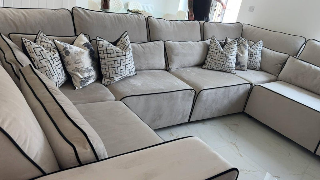 Large U-shaped cream sofa with black piping and patterned scatter cushions in a modern living room