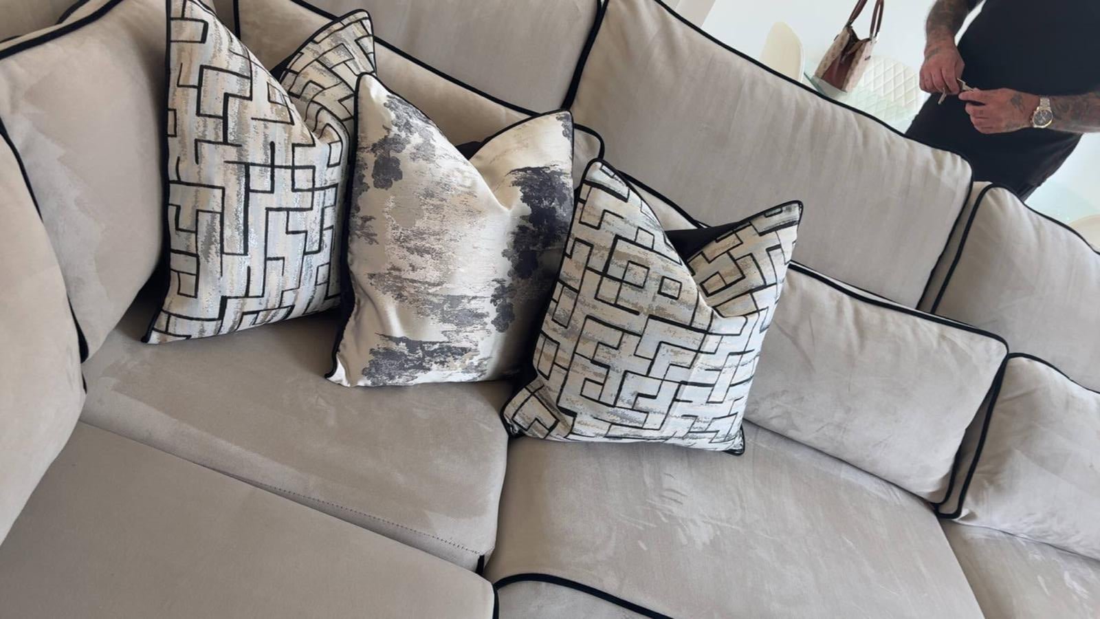 Cream U-shaped sofa with black trim and decorative patterned cushions in a modern living room