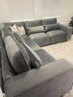 Large grey modular corner sofa with plush cushions in a modern living room setting