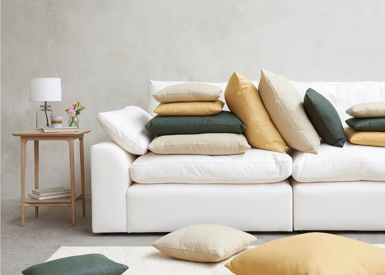 Cream modular sofa with assorted beige, yellow, and green cushions in a modern living room