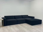 Modern black corner sofa with chaise lounge in a minimal living room on wooden flooring