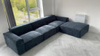 Modern dark blue L-shaped sofa with large removable footstool in a bright living room