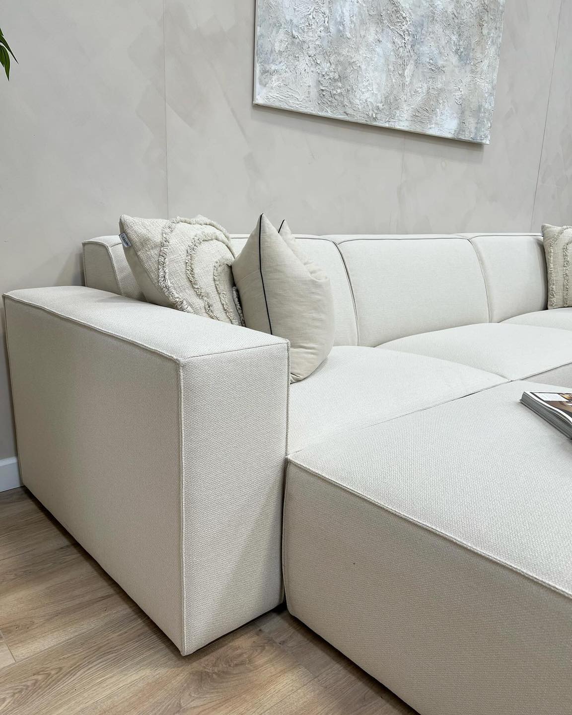Ivory modular sofa with removable footstool and accent cushions in modern living room