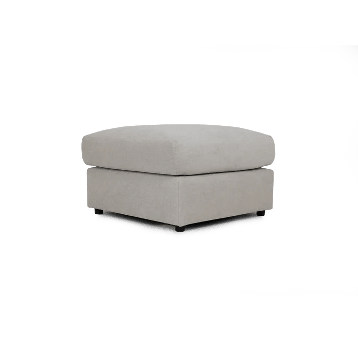 Cream fabric ottoman footstool with modern, boxy design on a white background