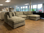 Large U-shaped silver full-back sectional sofa with plush cushions in a modern showroom