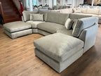 Large U-shaped silver velvet sofa with full back and scatter cushions in a modern showroom
