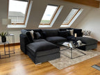 Large U-shaped silver sectional sofa in a modern loft with skylights and coffee table