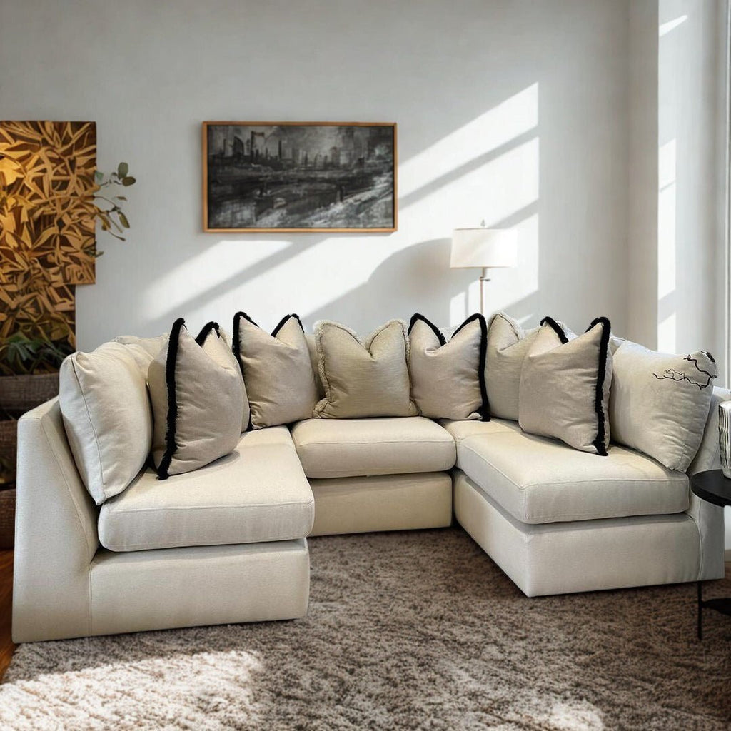 Modern beige corner sofa with plush cushions in a bright living room with neutral decor.