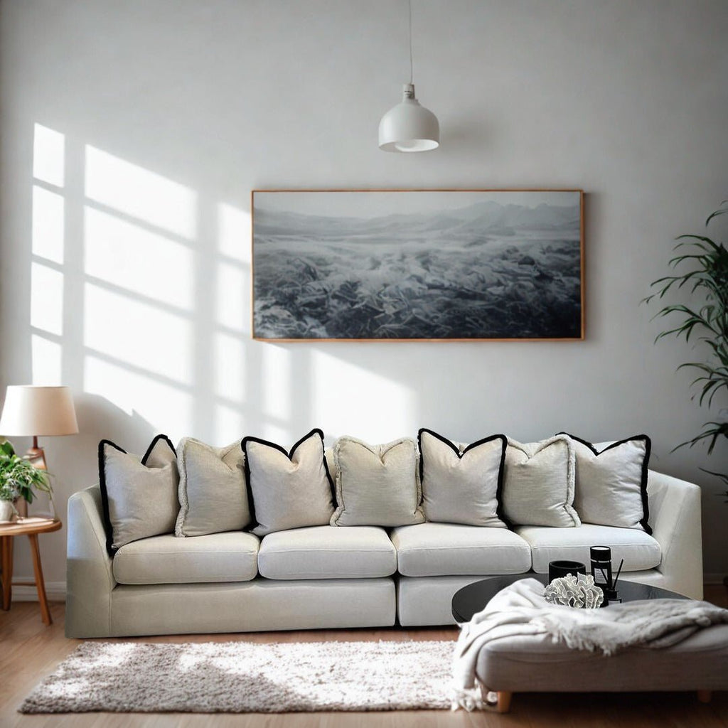 Modern living room with a large cream sofa, neutral cushions, and minimal decor