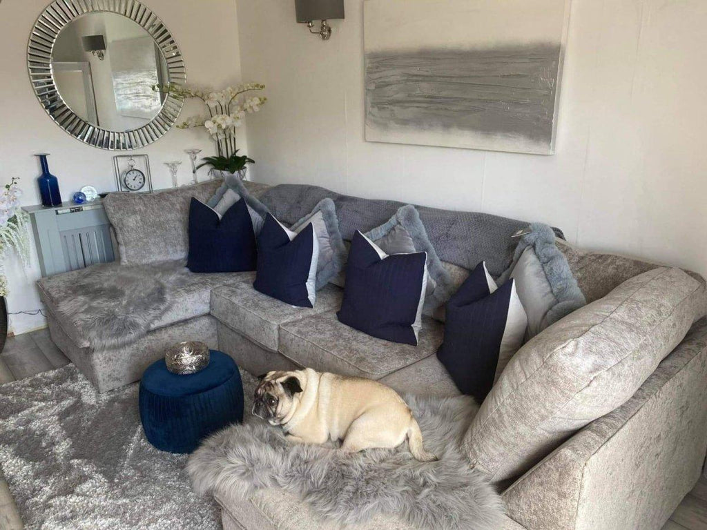 Large U-shaped sectional sofa in neutral fabric with navy cushions, decorated living room, dog resting on corner.