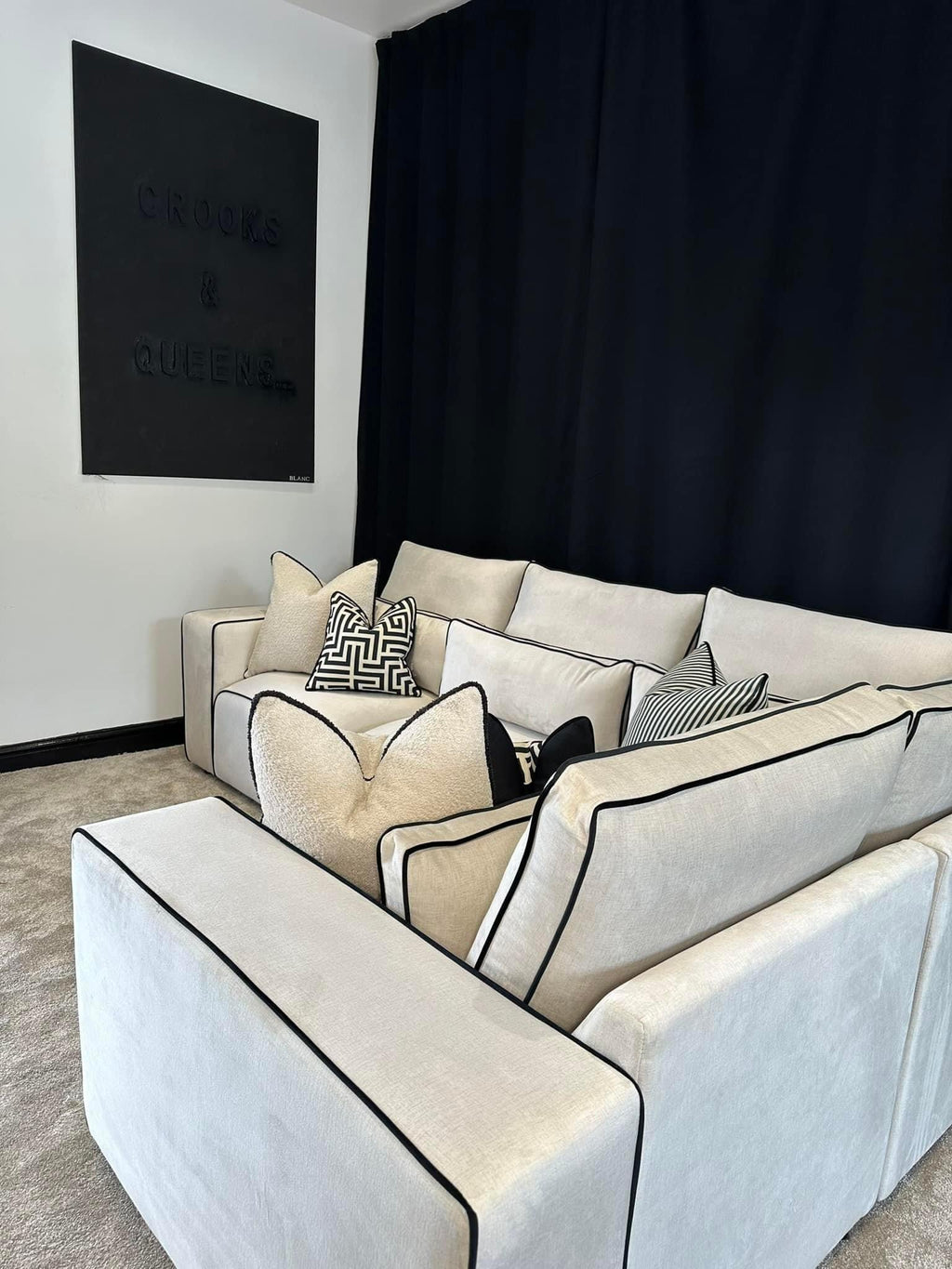 Modern white modular corner sofa with black piping and patterned cushions in a stylish living room