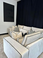 Modern white modular corner sofa with black piping and patterned cushions in a stylish living room