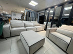 Modern white sofa set with black piping, armchair, and footstool in a showroom setting