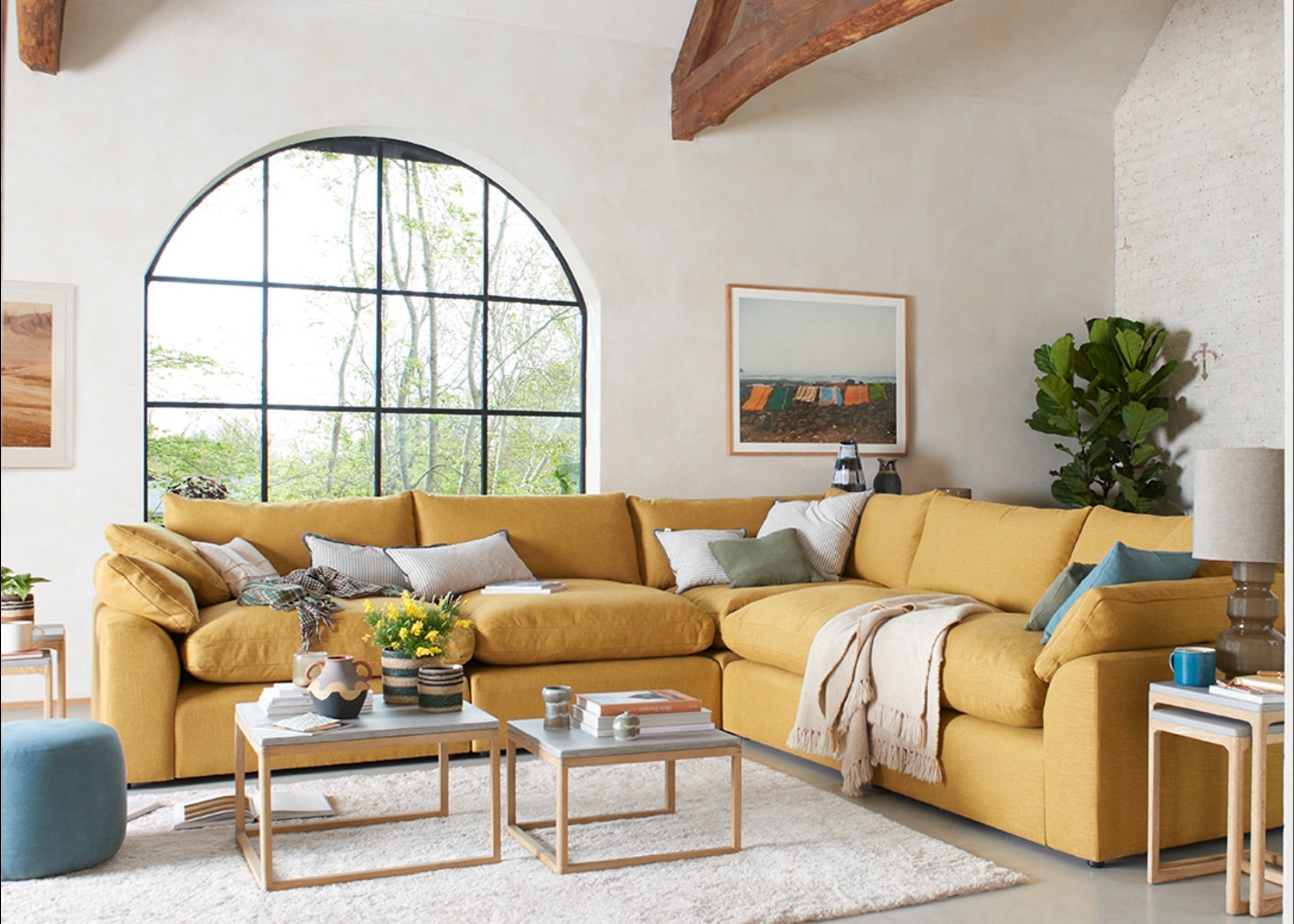Yellow modular corner sofa with cushions in a bright living room with large arched window