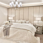 Cream velvet upholstered headboard wall panels behind a stylishly dressed bed with soft bedding.