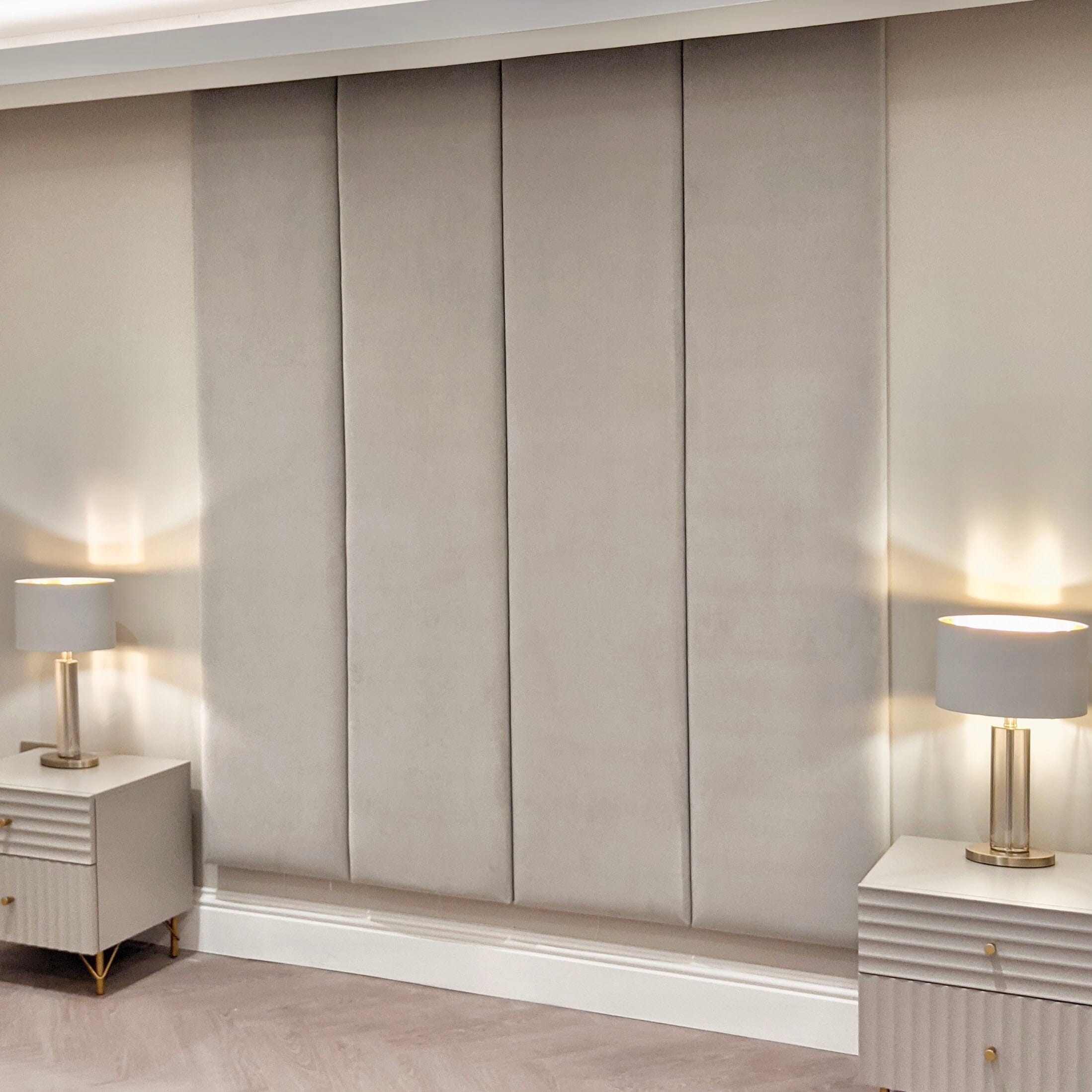Cream velvet upholstered headboard wall panels with modern bedside tables and lamps