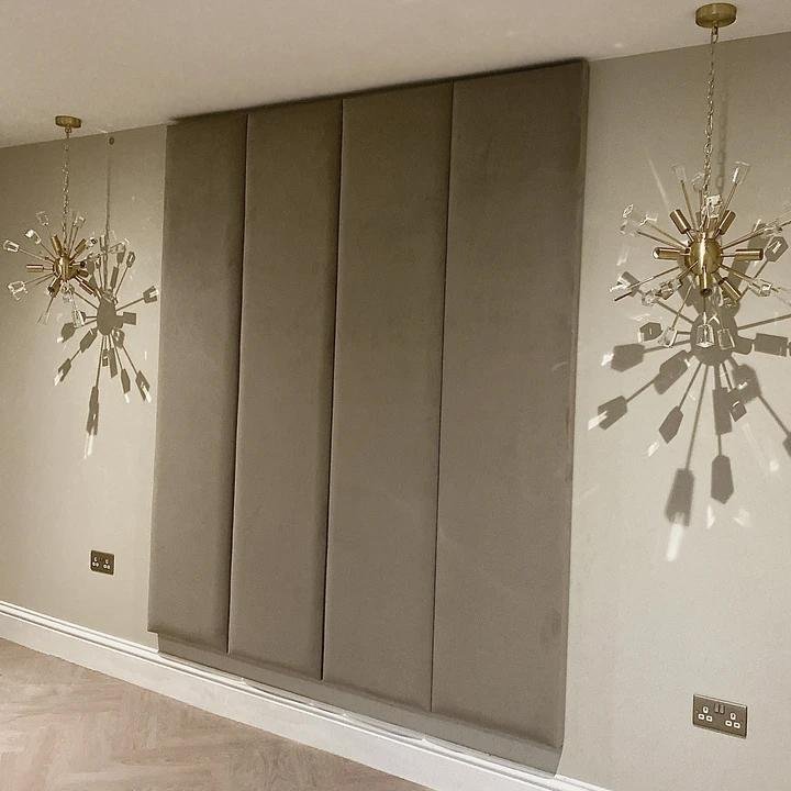 Cream velvet upholstered wall panels with gold pendant lights in a modern bedroom setting