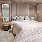 Cream velvet upholstered headboard wall panels behind a modern bed with neutral bedding