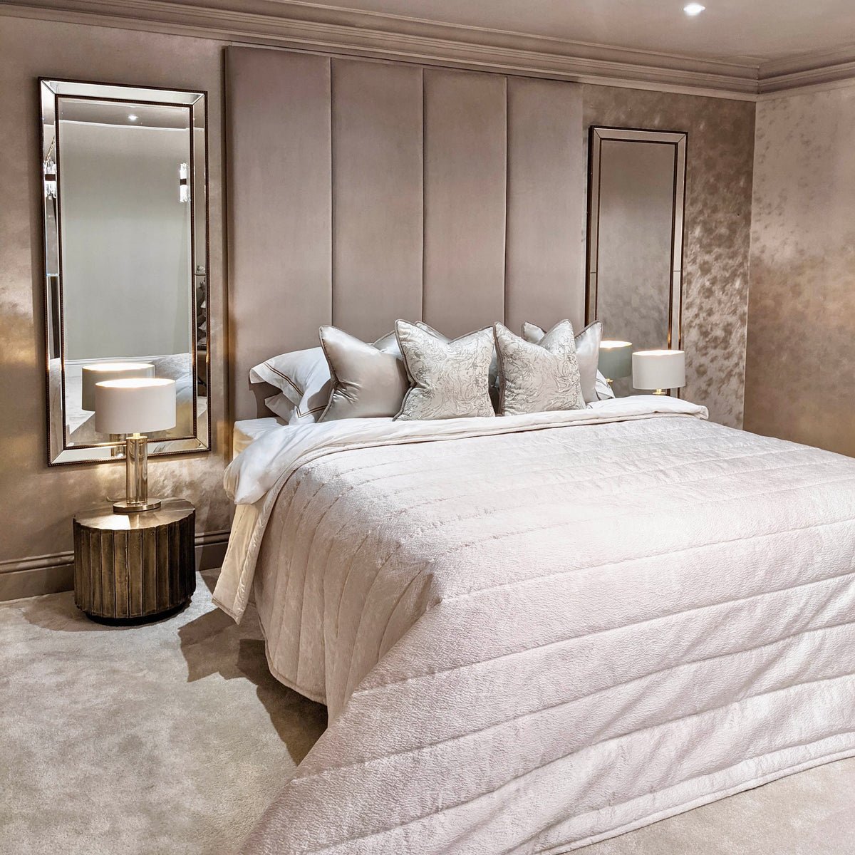 Cream velvet upholstered headboard wall panels behind a modern bed with neutral bedding