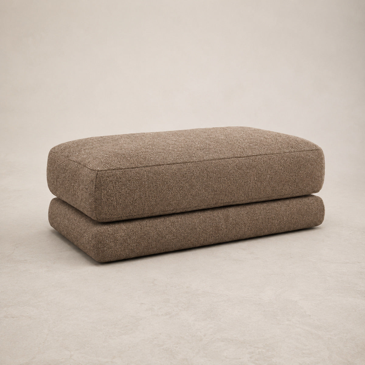 Aurelia Large Footstool in Coffee on a clean stone studio background