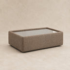 Aurelia Upholstered Rectangle Glass-Top Table in Coffee on a clean stone studio background