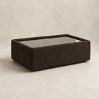 Aurelia Upholstered Rectangle Glass-Top Table in Double Espresso on a clean stone studio background