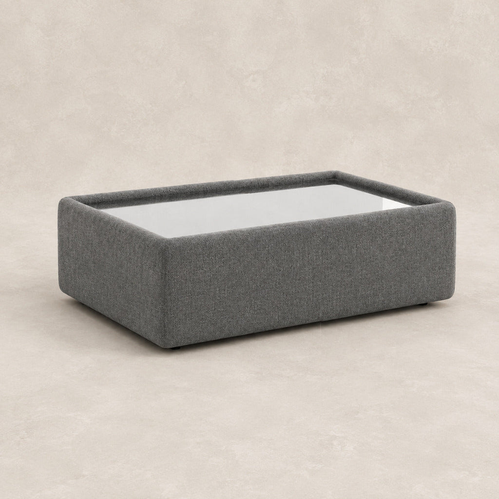 Aurelia Upholstered Rectangle Glass-Top Table in Luxe Steel Grey on a clean stone studio background