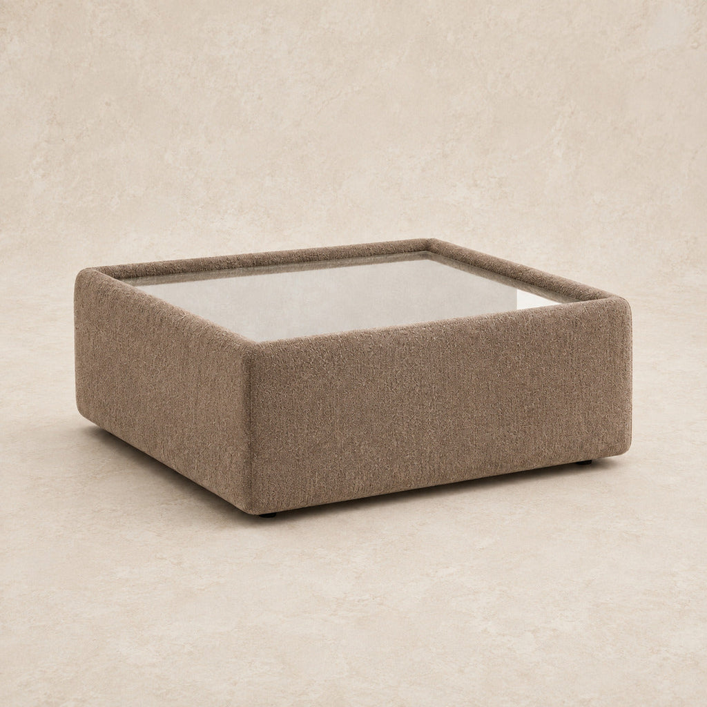 Aurelia Upholstered Square Glass-Top Table in Coffee on a clean stone studio background