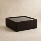 Aurelia Upholstered Square Glass-Top Table in Double Espresso on a clean stone studio background