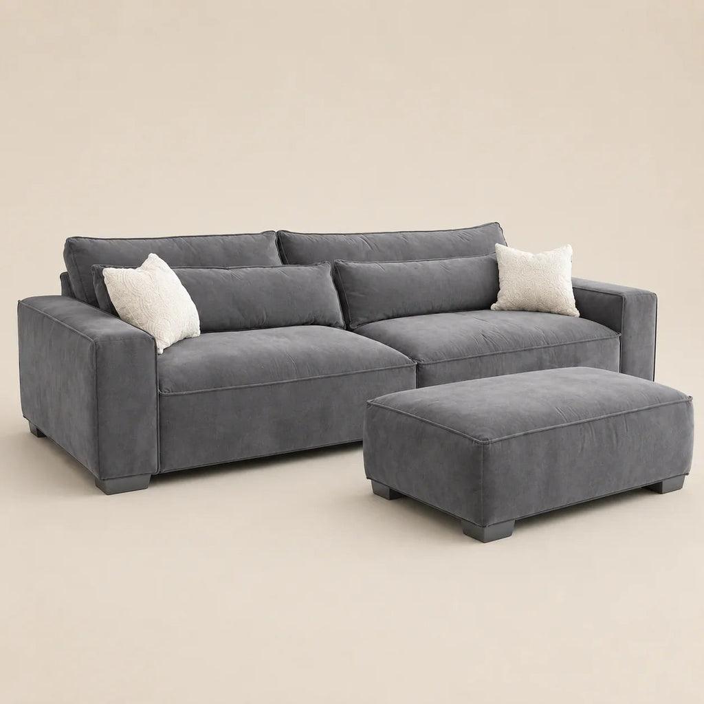 Grey velvet sectional sofa with matching ottoman and white throw pillows, modern luxury living room furniture