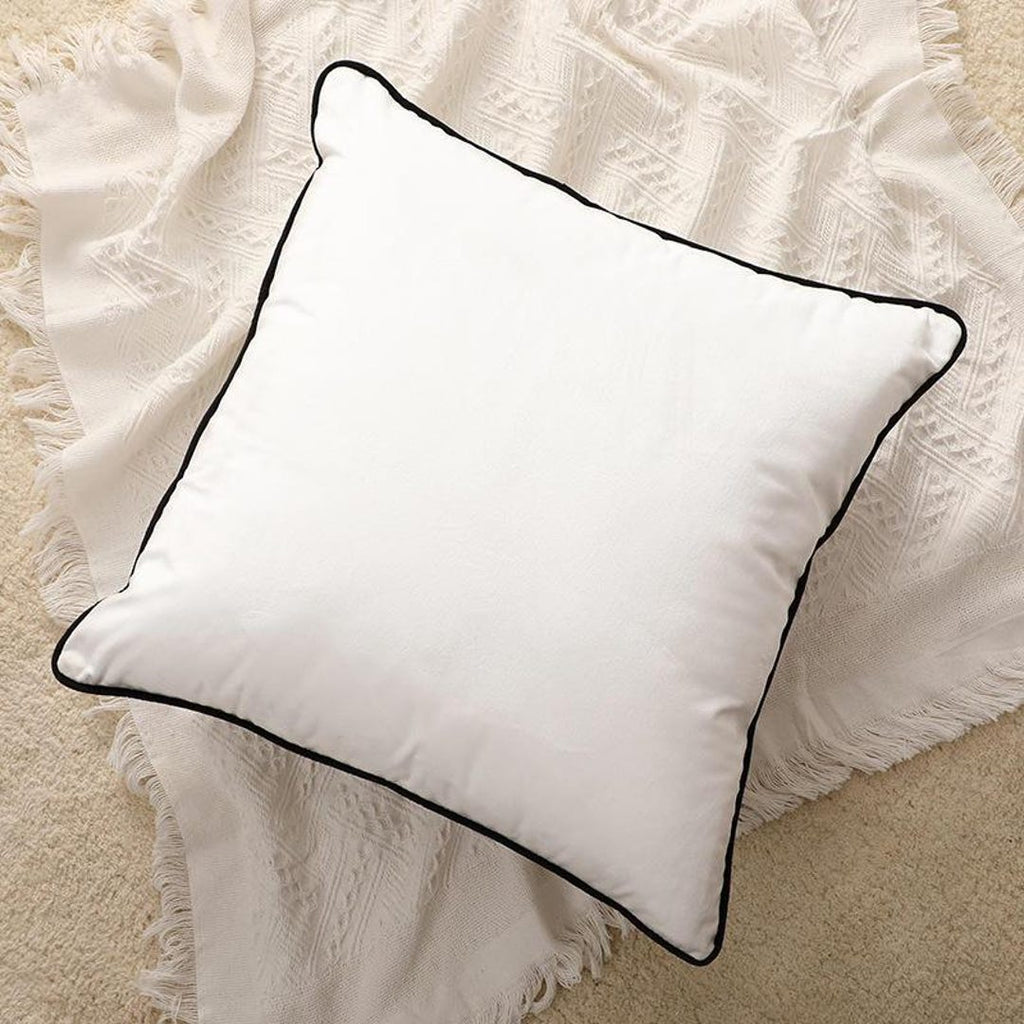 White square cushion with black piping on textured cream throw, luxury home decor