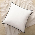 White square cushion with black piping on textured cream throw, luxury home decor