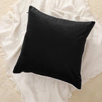 Black velvet cushion with white piping on textured cream throw blanket