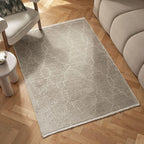 Beige geometric pattern rug on herringbone wood floor beside modern sofa and armchair