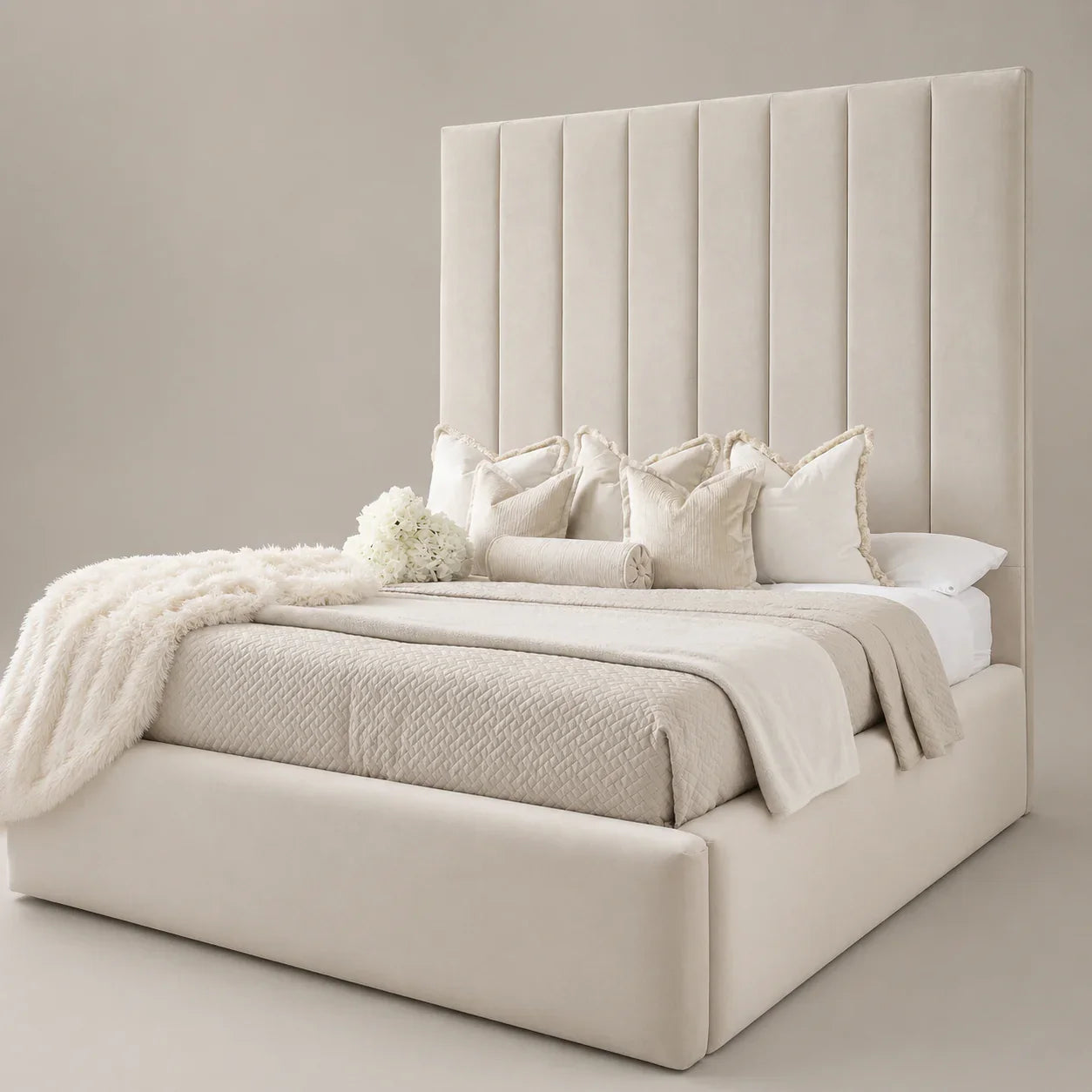Luxury beige upholstered bed with tall tufted headboard, plush pillows, and cozy throws for modern bedroom decor