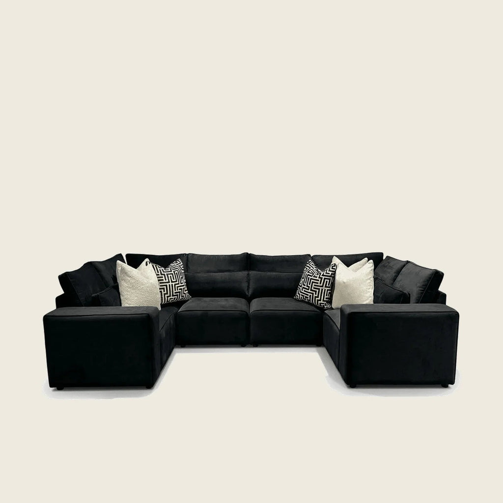 Black velvet sectional sofa with geometric and cream throw pillows, modern luxury living room furniture