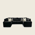 Black velvet sectional sofa with geometric and cream throw pillows, modern luxury living room furniture
