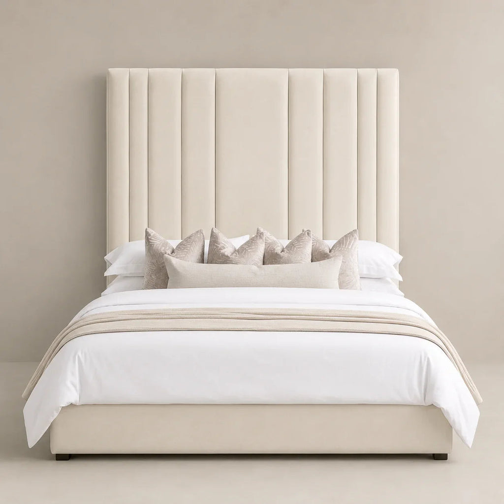 Luxury beige upholstered bed with tall tufted headboard, white linens, and decorative pillows