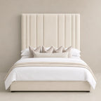 Luxury beige upholstered bed with tall tufted headboard, white linens, and decorative pillows