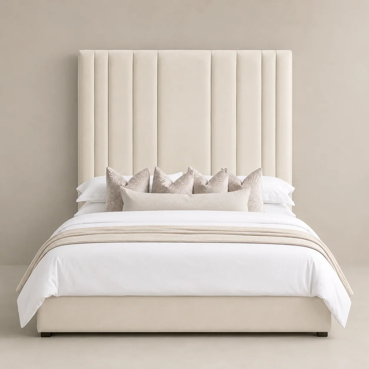 Luxury beige upholstered bed with tall tufted headboard, white linens, and decorative pillows