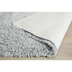 Soft grey shaggy rug with textured cream backing on light wood floor