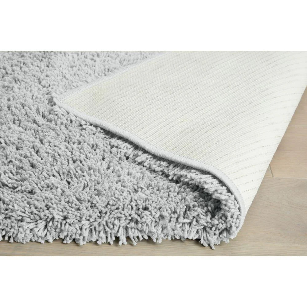 Soft grey shaggy rug with textured cream backing on light wood floor