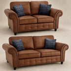 Brown leather two-seater sofa with rolled arms, nailhead trim, and plaid pillows, ideal for luxury living rooms.