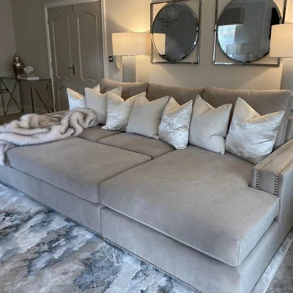 Large mink sectional sofa with studded arms, plush cushions, and throw blanket in modern living room