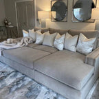 Large mink sectional sofa with studded arms, plush cushions, and throw blanket in modern living room